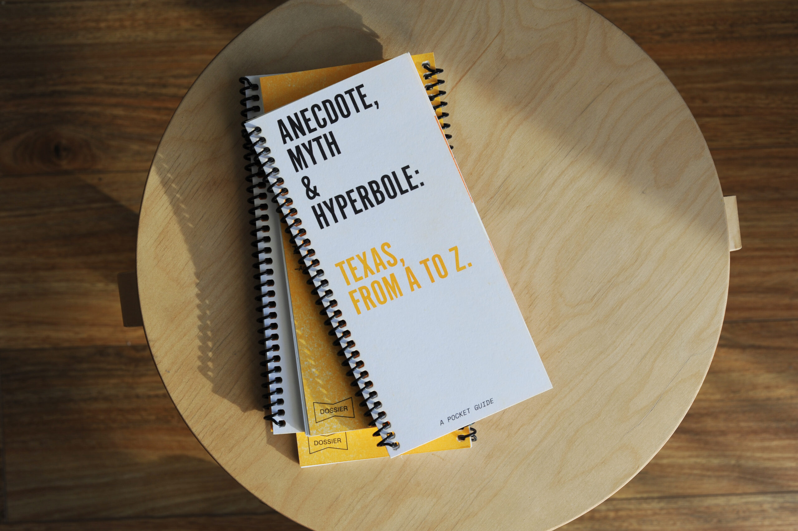 stack of spiral bound books titled Anecdote, Myth & Hyperbole: Texas, from A to Z. A pocket guide